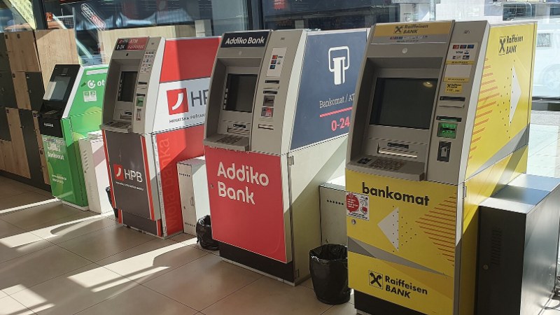 Un distributeur automatique de billets installé dans la rue, écran allumé.