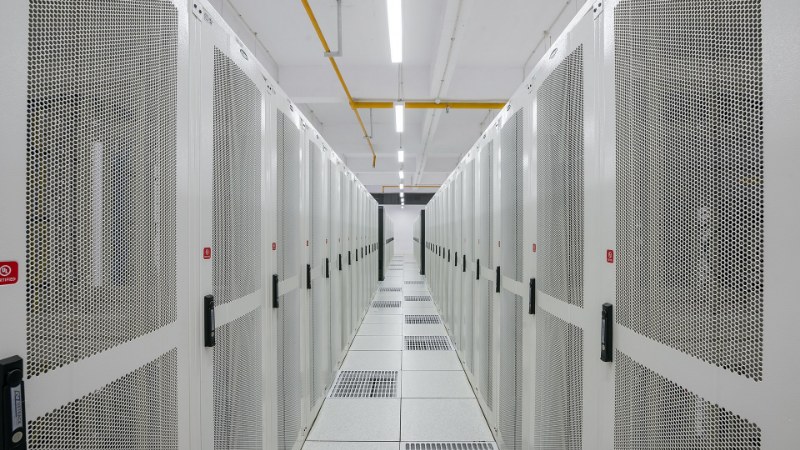 Couloir d’un centre de données blanc, baies serveurs perforées de part et d’autre