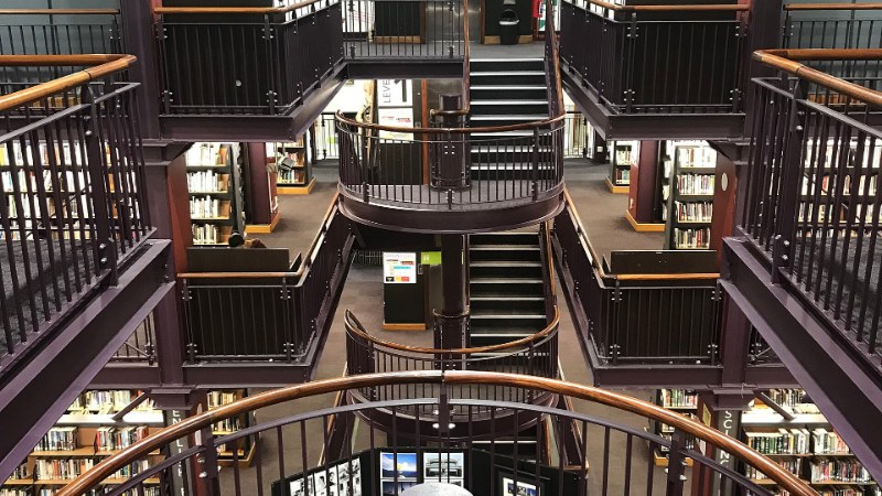 Intérieur de la bibliothèque centrale du Cap : des galeries à balustrade sur plusieurs niveaux, garnies de rayonnages de livres, autour d’un vide central où montent des escaliers ; un panneau indique « LEVEL 2 »