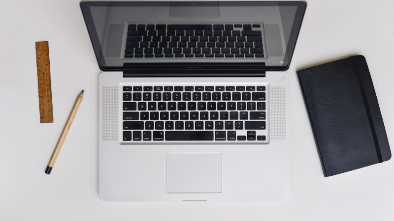 Un ordinateur portable Apple ouvert sur un bureau en bois