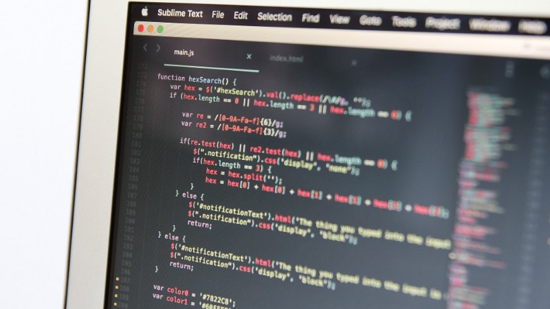 Gros plan sur l’écran d’un ordinateur portable affichant du code JavaScript dans un éditeur de texte, le clavier flou au premier plan