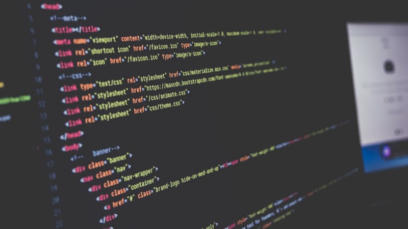 Écran d’ordinateur affichant du code source HTML coloré, photographié de biais