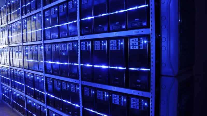 Des baies de serveurs alignées dans une salle informatique, panneaux avant éclairés de bandes bleues